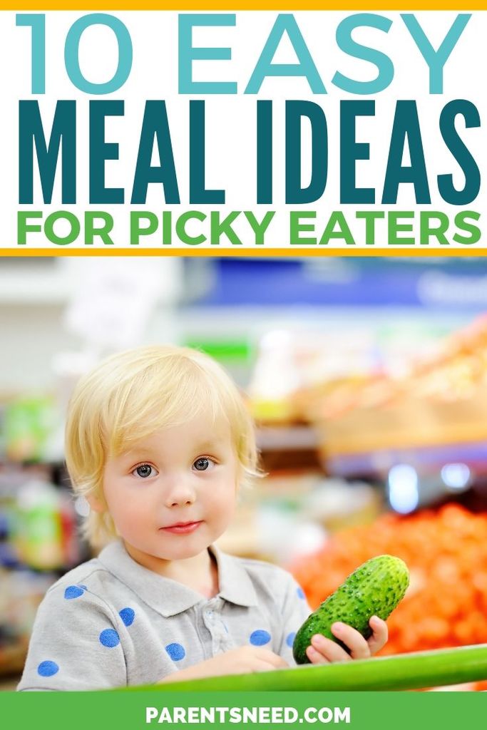 A toddler holding up a cucumber at a supermarket