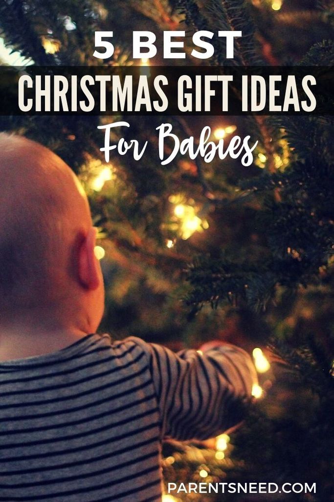 A baby reaching with wonder towards a Christmas tree
