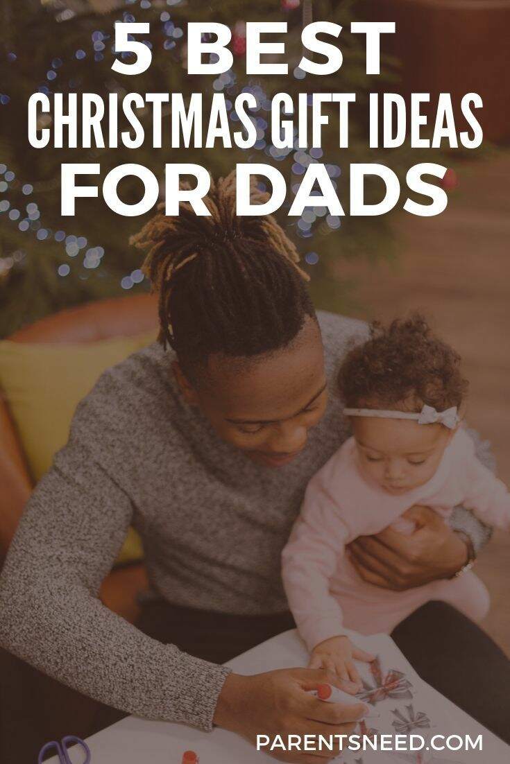 A Dad holding his toddler in front of a Christmas tree